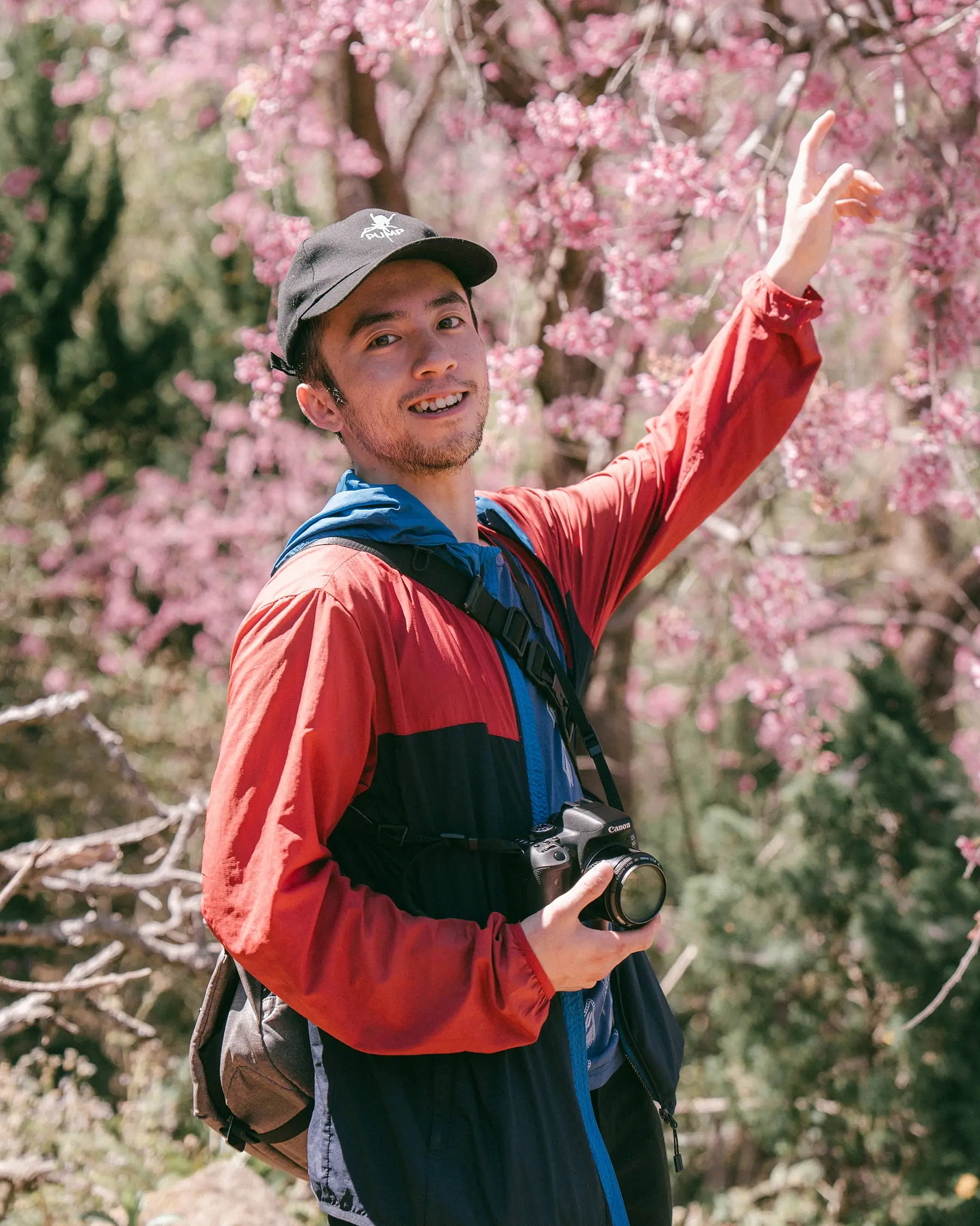 Den's cofounder, Maxi, standing with a camera among cherry blossoms